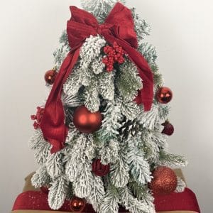 Brăduț decorativ de masă Crăciun cu cetină înzăpezită, fundă roșie și globuri roșii